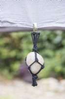 Large pebble in black string net hanging from table cloth