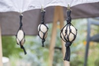 Large pebbles in black string net hanging from table cloth