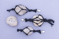 Large pebbles in black string laid out on cloth