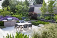 Outdoor dining and barbecue area on terrace of modern garden