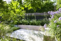 Sheltered seating area in modern garden with lush planting and built-in bench seating