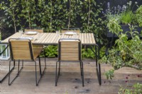 A reused timber floor patio area - outdoor dining table and chairs in courtyard with black wooden fence - Finnish Soul Garden Chelsea flower Show September 2021