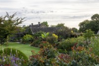 View from the raised walk across to tropical-style planting in the Warm Border at Bourton House Garden, Gloucestershire