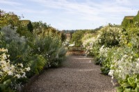 View down the gravel path in the White Garden towards the raised pond at Bourton House Garden, Gloucestershire.