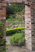 A doorway in the brick wall frames a view of the tulips parterre.