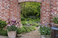 The main entrance to the kitchen garden frames a view of the pond and shady woodland area beyond.