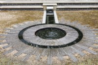 A rill with metal casings that lead into double circles. The circular water feature is set into a sun style design created from laying slates on their sides.