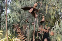 Several rusty, metal garden sculptures of flowers and leaves including snowdrops and ferns. The Garden House, Yelverton. Autumn, November