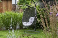 A corner of a lawn provides a cool, sheltered spot for a swing chair.