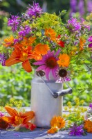 Summer bouquet in a milk churn containing coneflowers, fennel, hemerocallis, bergamot and pot marigold.
