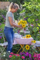 Woman placing a vase with sunflowers on the table.