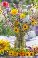 Summer bouquet containing pot marigold, persicaria and  wild carrots in a glass vase.