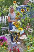 A woman creates a flower bouquet with sunflowers, dahlias and chamomiles.