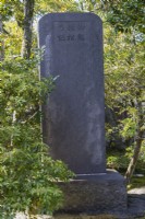 Rectangular stone sentinel in the garden with inscription in Japanese. 