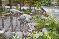 Pond with pebbles in 'A Glimpse of South East Asia' garden at BBC Gardeners World Live 2019, June