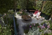 Landform Mental Wealth Garden. Designer: Nicola Hale. Overview of garden with Nicola Hale and Jaynie Tricker - Potter and Intuitive Energy Worker - Planting for aromatherapy and pollinators. Woven willow with Tracheleospermum jasminoides screen the garden. Summer. 