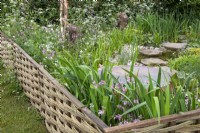 Woven willow fence with a wildflower planted garden and water feature