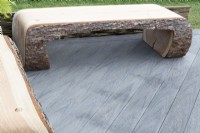 Modern contemporary bench seat made from tree trunks on a composite board deck