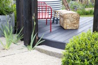 Gravel path with curved stone step up to circular composite board raised deck
