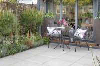 Garden building and seating area surrounded by planting in 'The Home Solutions by John Lewis Garden' at BBC Gardeners World Live 2019