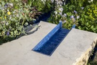 A modern contemporary water rill made from recycled plastics set in stone