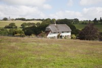 Farmhouse surounded by fields with post and rail fencing, countryside views and church views .