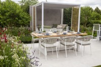 Outdoor dining table and chairs with a covered pergola seating area - mixed perennial planting of Lavender, Astrantia major, Lupins and Monarda flowers, Lower Barn Farm: The Bounce Back Garden