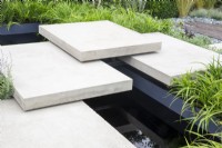 Floating concrete stone stepping stones steps over a black rill