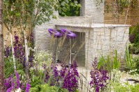 A stone dining area with purple bar stools, mixed perennial planting in purple and white colours