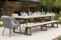 Dining table, chairs and wooden bench on a terrace with an outdoor room - stone paved patio 