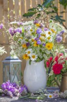 Summer flower arrangement with wildflowers including daisies, yellow ox-eye, wild carrots, campanula, allium and red roses.
