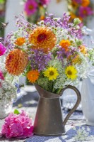 Summer bouquet in metal jug containing Dahlia, Helianthus, Calendula, Allium and Daucus carota.