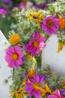 Detail of the wreath made of Dahlia, Rudbeckia, Calendula and Clematis seedheads hanging from a fence.