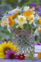 Annual flower bouquet featuring Nasturtium, Pot marigold, Wild carrot and Love in a mist in a glass jar decorated with twine.