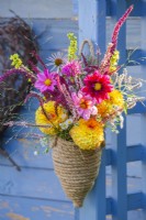 Summer flower bouquet with Dahlia, Monarda, Echinacea purpurea, persicaria amplexicaulis, Verbascum and Amaranthus caudatus in a rope hanging vase.