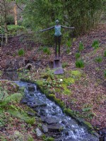 Bronze scupture of a female swimmer  beside a stream at Rosemore RHS Garden in Devon, February. 
