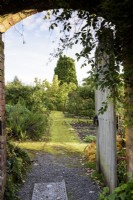 View through a gate into a walled vegetable garden with mossy path in October