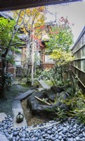 Small courtyard with granite pebbles and narrow stone slab path with stone on path tied with string to indicate no entry. This is called Tome ishi. Water feature with small pool.