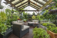 Balinese style outdoor covered patio with lounges, hanging baskets and potted plants.