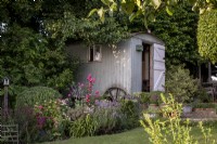 Shepherd's hut in summer garden, hidden amongst shady mature trees