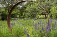 Clary sage and other perennial wildflowers around a Corten steel moon gate.