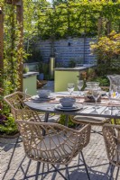Dining area with a table and chairs surrounded by a wooden pergola with Trachelospermum jasminoides - star jasmine, heucheras and ferns. Relaxation space at the back. Designer: Colm Carty