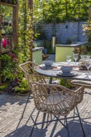 The dining area with a table and chairs is surrounded by a wooden pergola with Trachelospermum jasminoides - Star jasmine., heucheras and ferns. Corner with a firepit at the back. Designer: Colm Carty