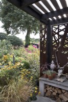 Late summer garden with contemporary covered area in wood and corten metal, beyond a bed with Rudbeckia 'Goldsturm',
Cosmos bipinnatus 'Dazzler' and Echinops
