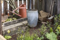 Small wooden compost bin, watering can and water barrel in vintage style