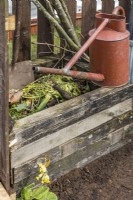 Small wooden compost bin and watering can in vintage style