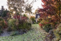 Borders full of trees and shrubs turning colour in autumn at Wild Thyme Cottage