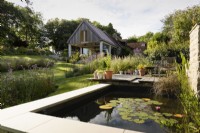 Lily pond in a country garden in July with contemporary extension beyond.