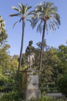 A figurative statue of a woman on a stone plinth. Parque de Maria Luisa, Seville, Spain. September