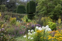 Mixed perennials and topiary in summer borders in the Flower Garden at The Manor, Little Compton.